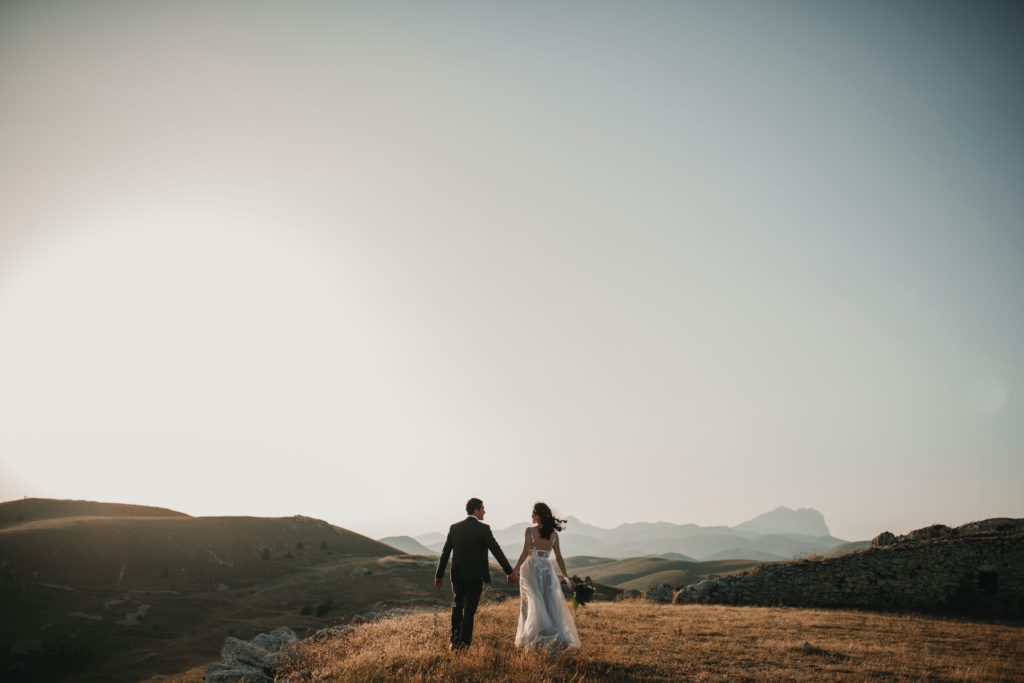 Mariés qui se tiennent la main et paysage de montagne. coaching organisation de mariage. Paris en noces. Wedding planner en ile de france