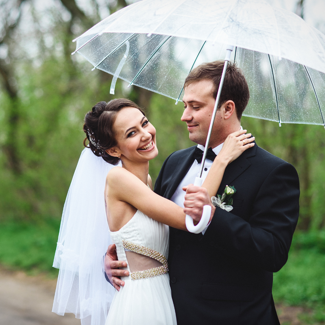 Couple face à face dans les bras l'un de l'autre sous un parapluie transparent. Mariage pluvieux. Wedding planner Ile de France. Paris en Noces