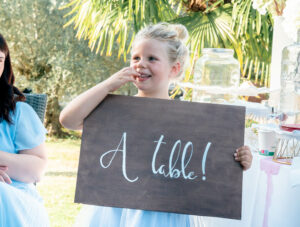 Petite fille blonde qui tient un panneau a table. Vin d'honneur. Wedding Planner en Ile de France. Paris en Noces